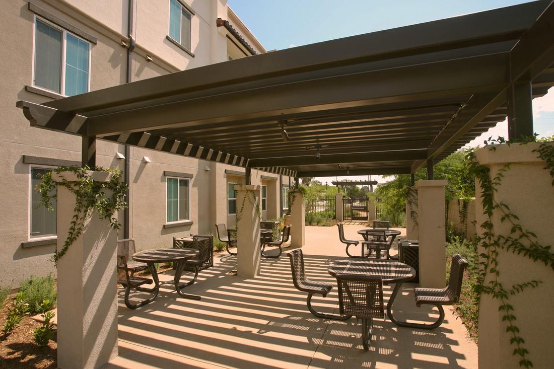a patio with tables and chairs under an awning.