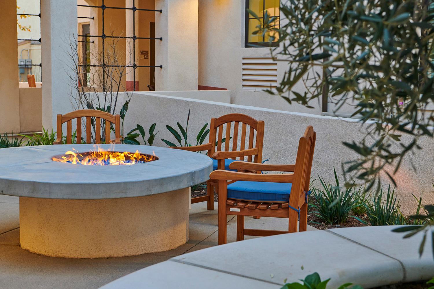 a fire pit with chairs around it on a patio.